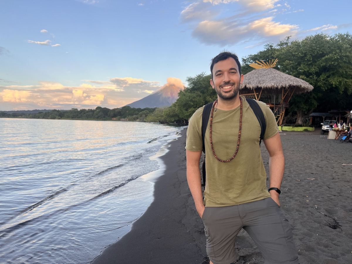 Roy on a lakeshore with a volcano behind him